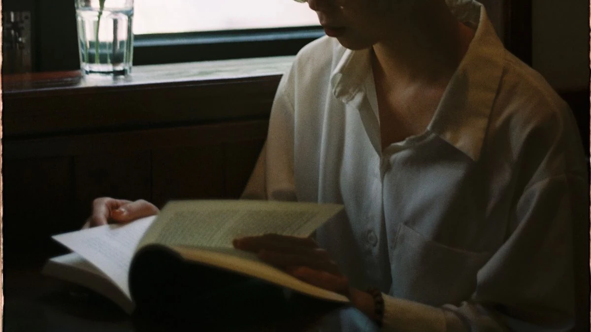 窓辺で本を読んでいる人の手元