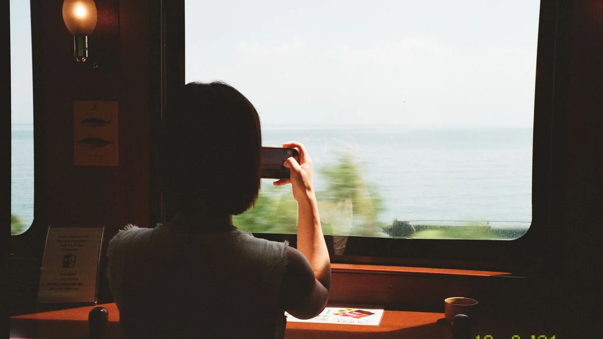 日本の列車の窓から海の景色を眺める旅人