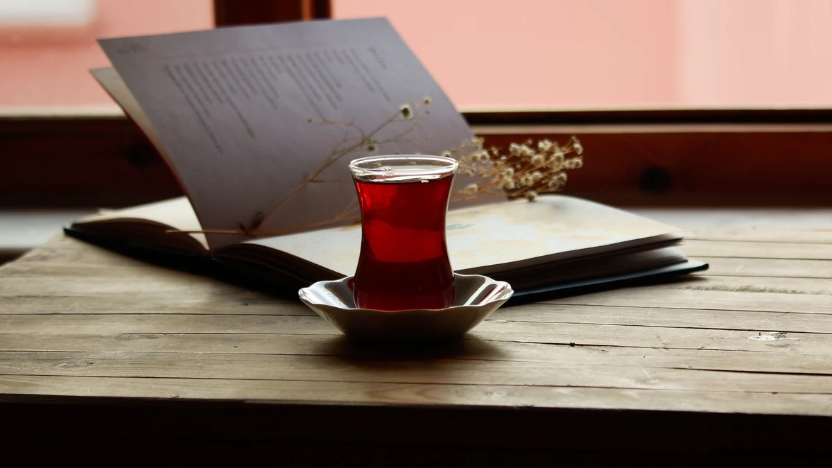 窓辺の木のテーブルに置かれた開いた本と紅茶