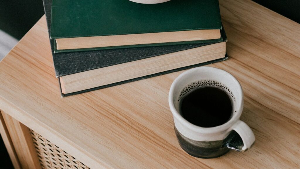 積み重ねた本とテーブルのコーヒーカップ